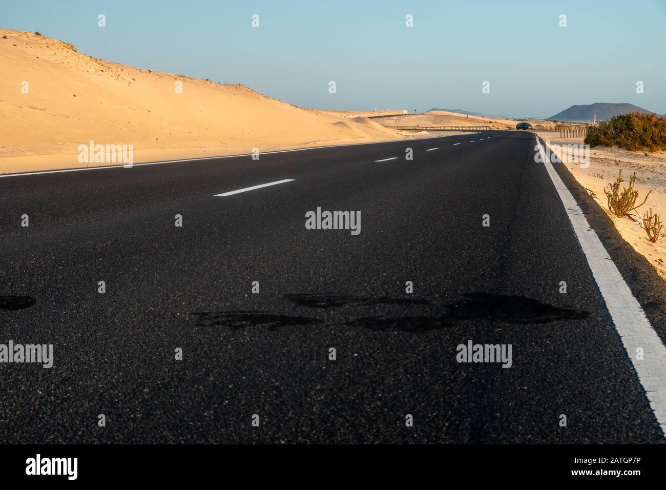 route asphaltée traversant le désert sablonneux au lever du soleil Banque D'Images