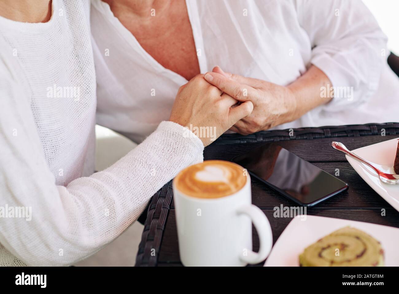 Image rapprochée de la fille rassurant sa mère et tenant sa main quand ils boivent du café ensemble Banque D'Images