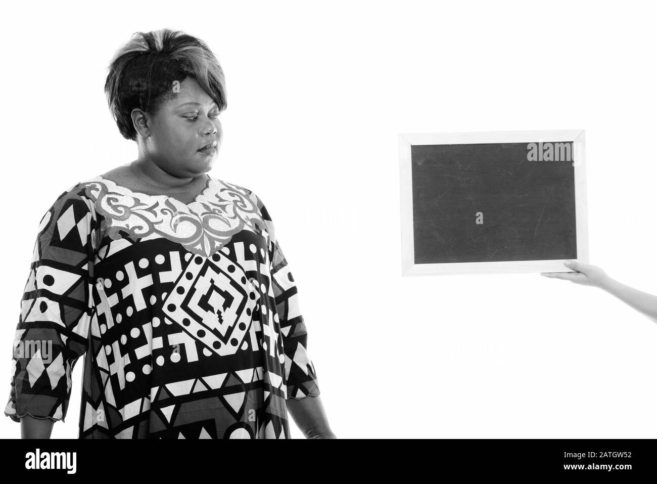 Studio tourné d'une femme africaine noire grasse regardant un tableau noir blanc Banque D'Images