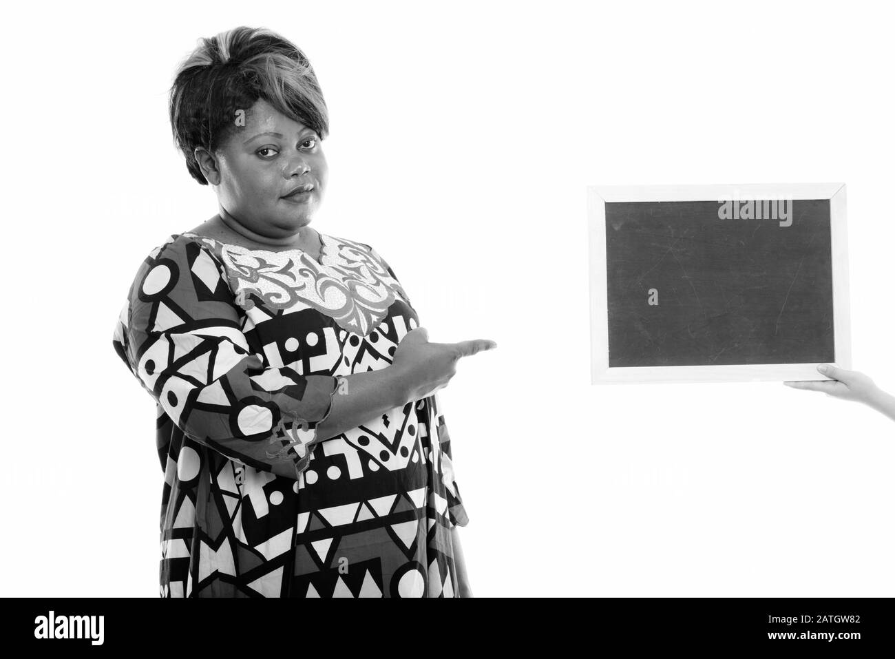 Studio tourné de graisse noire africaine femme pointant vers le tableau noir blanc Banque D'Images
