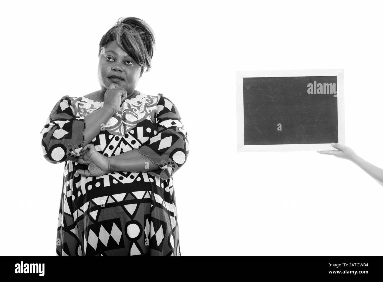 Studio tourné de grosse femme noire africaine pensant avec tableau noir blanc Banque D'Images