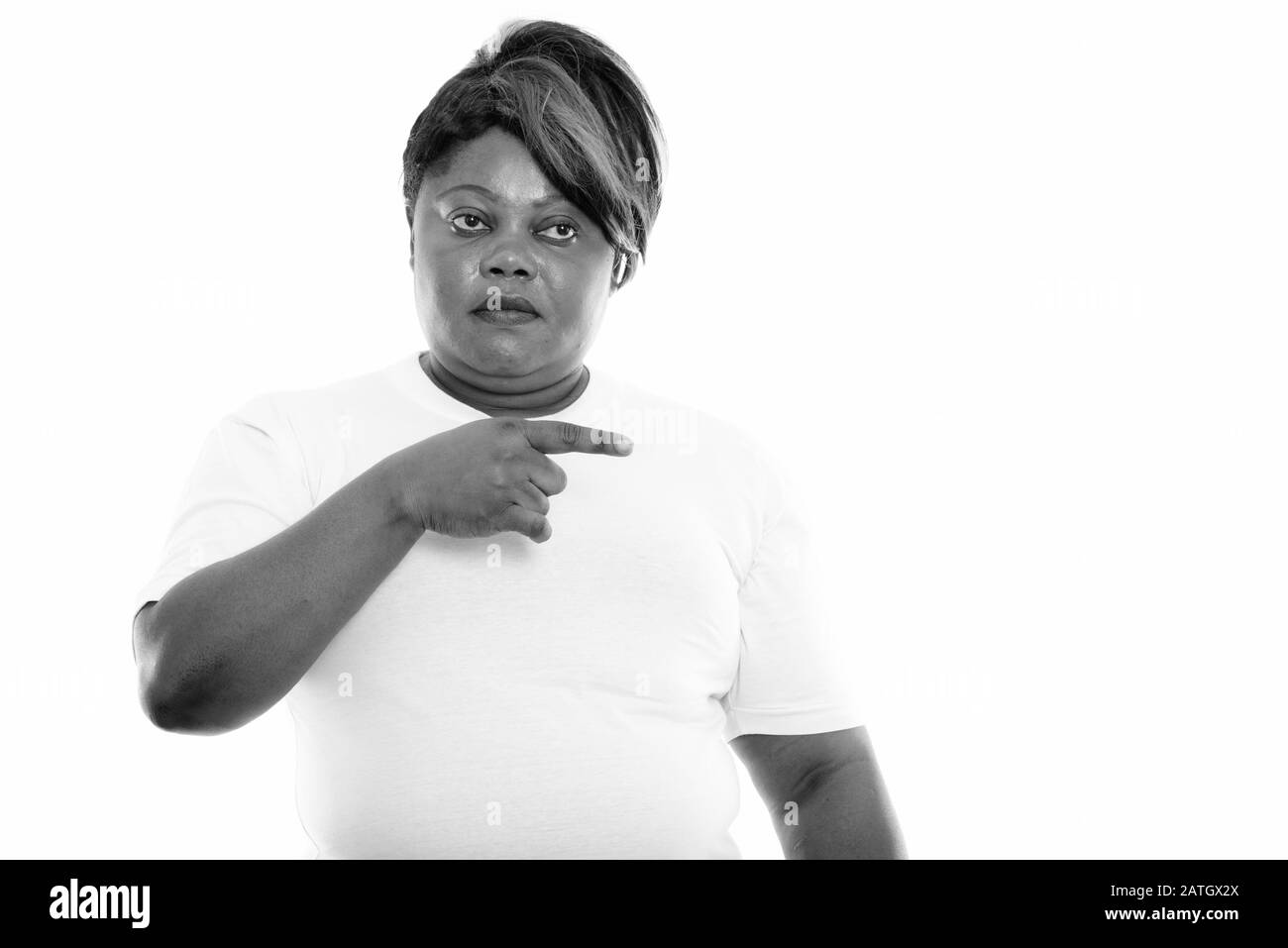 Studio tourné d'une femme africaine noire grasse pointant vers le côté tout en pensant prêt pour la salle de gym Banque D'Images