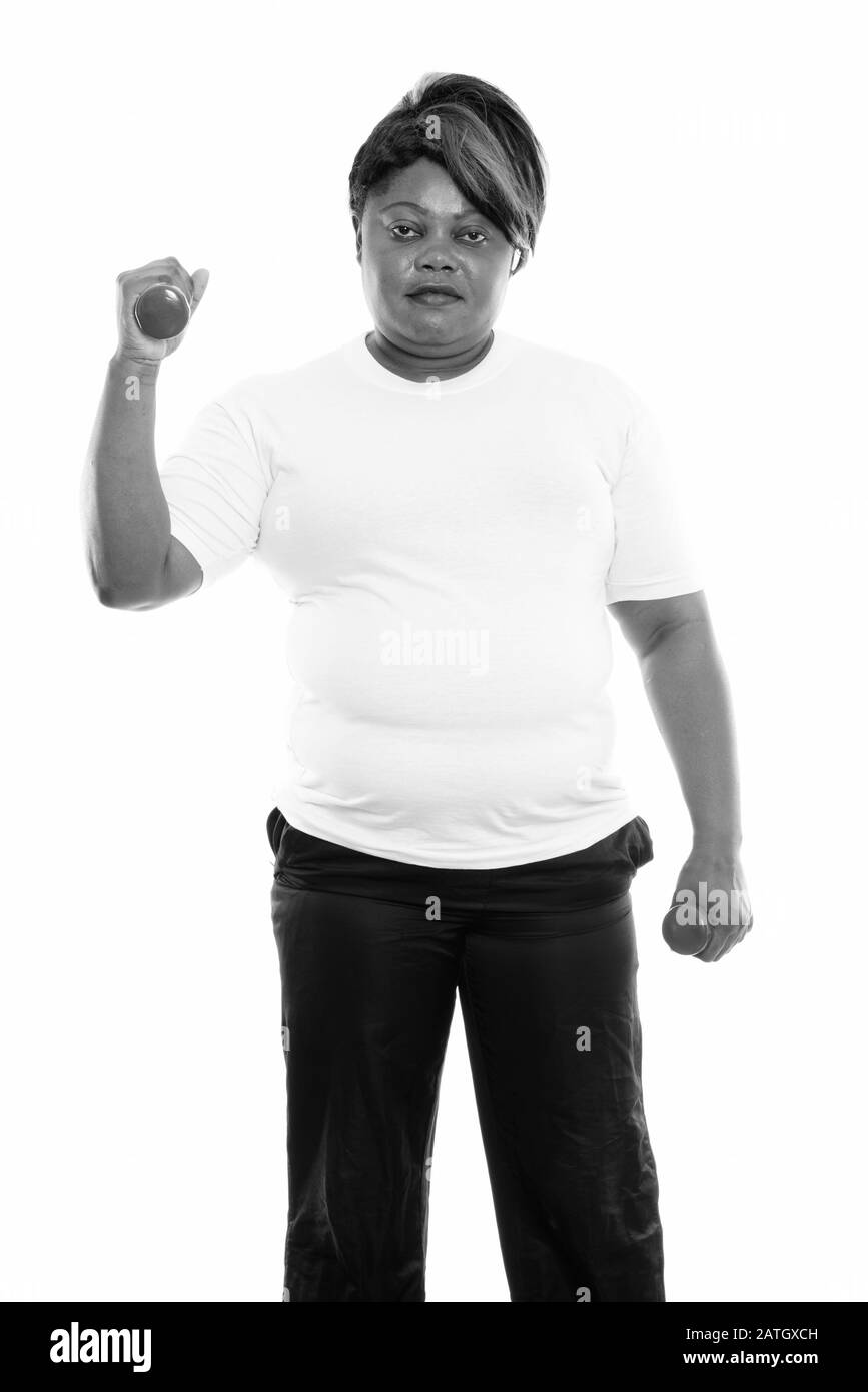 Studio tourné de grosse femme africaine noire debout tout en faisant de l'exercice avec des haltères prêts pour la salle de gym Banque D'Images