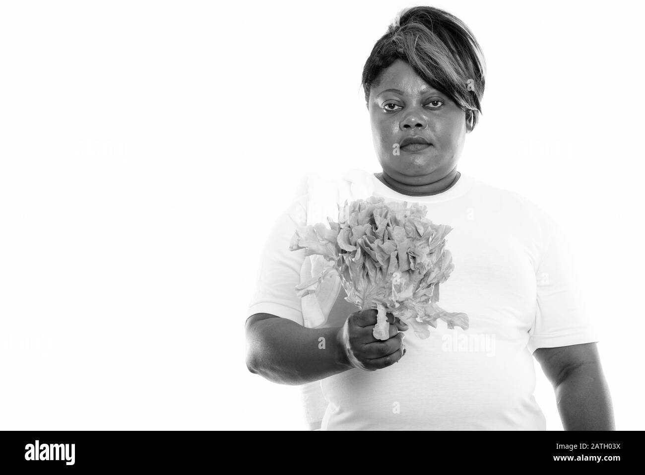Studio shot of fat black African woman holding lettuce Banque D'Images