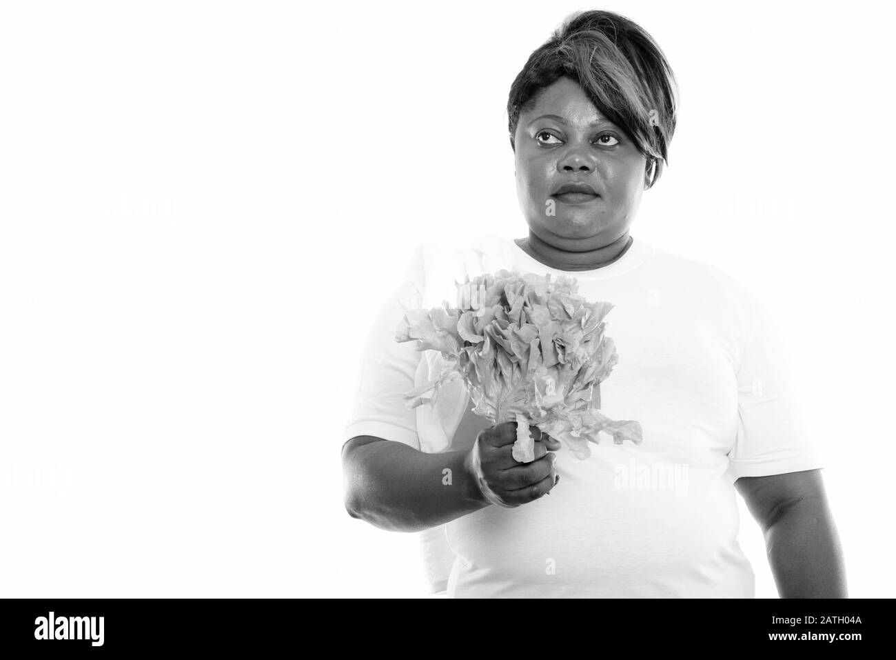 Studio tourné de graisse noire africaine femme pensant tout en tenant la laitue Banque D'Images
