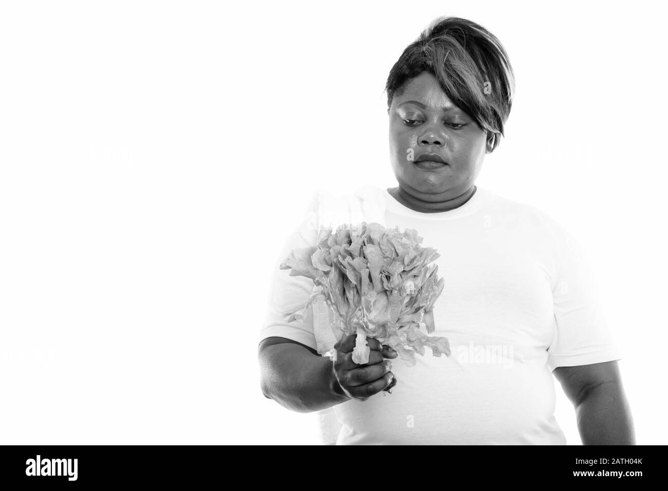 Studio tourné de graisse noire africaine femme tenant et regardant la laitue Banque D'Images