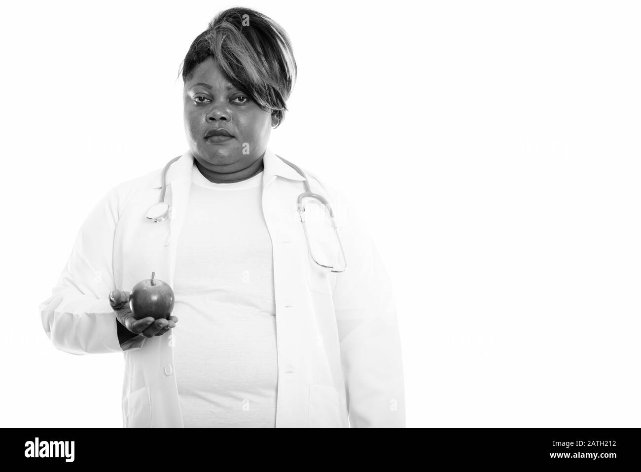 Studio tourné de graisse noire africaine femme médecin tenant la pomme Banque D'Images