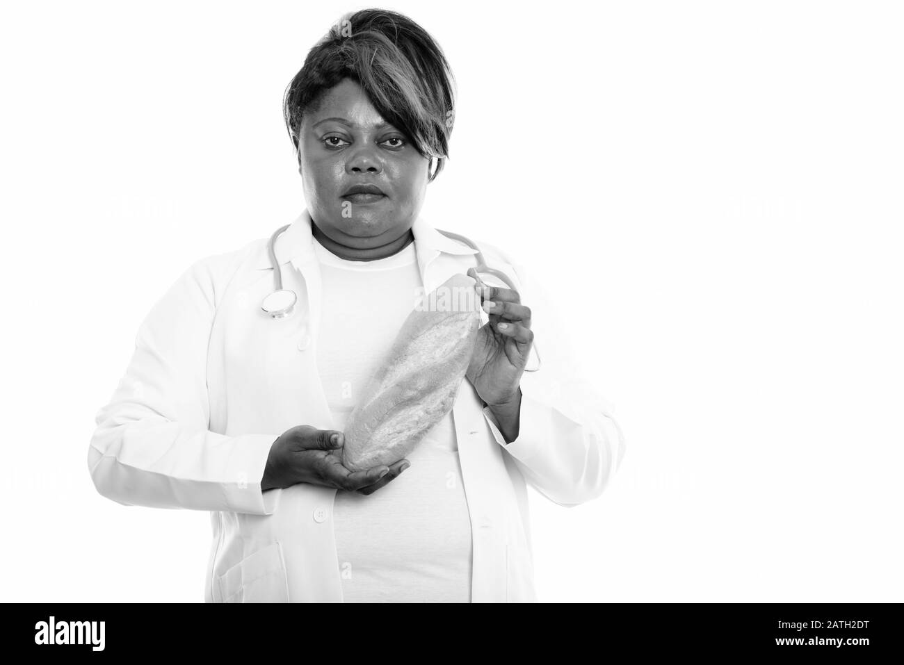 Studio shot of fat black African woman doctor holding pain Banque D'Images