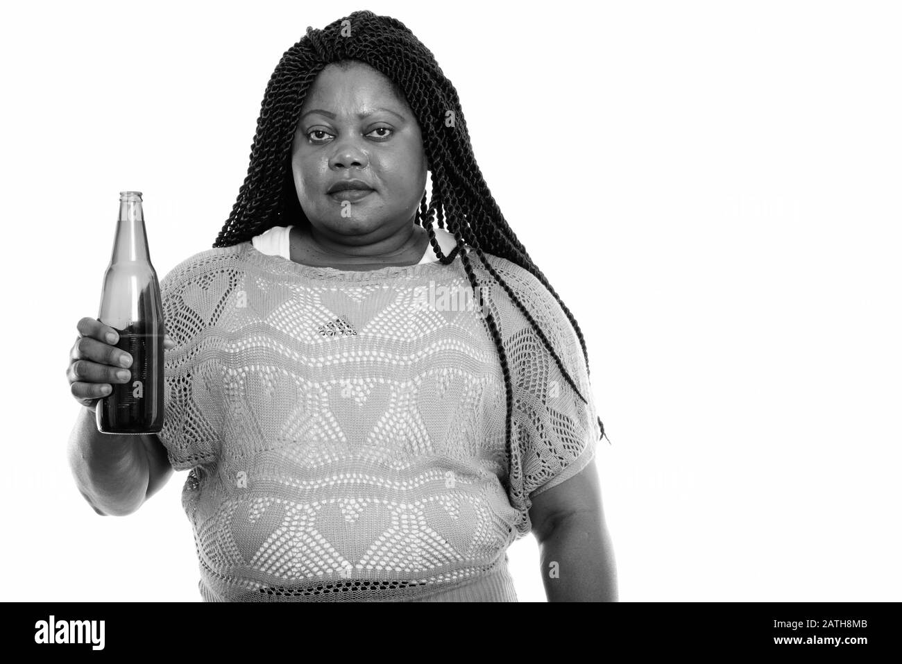 Studio shot of fat black African woman holding bouteille de bière Banque D'Images