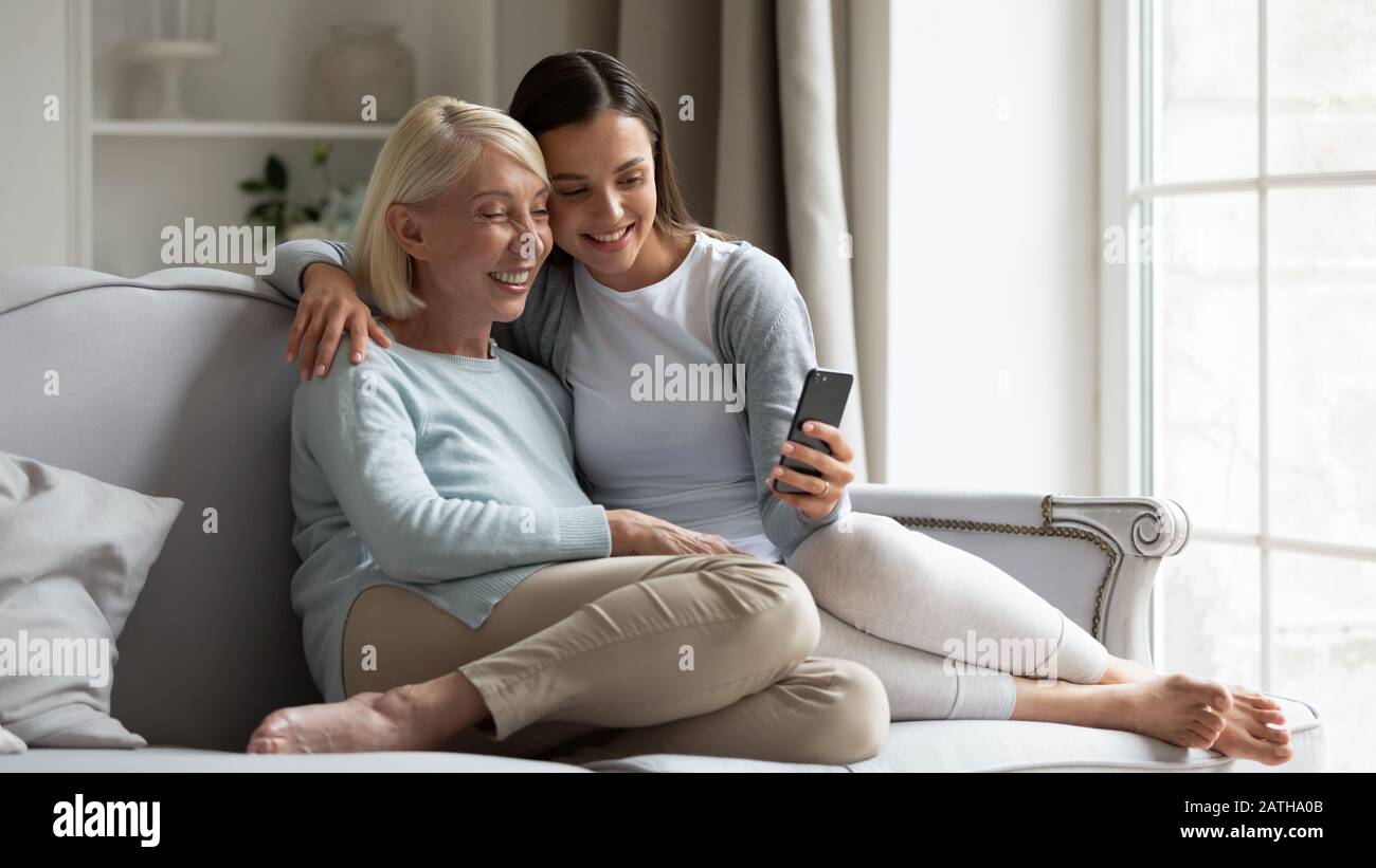 Une maman heureuse d'âge moyen et une fille grognée font du selfie sur smartphone Banque D'Images