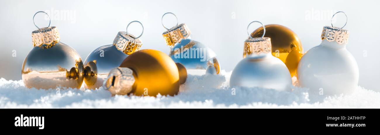 Boules de noël blanches et dorées dans la neige glacée, panorama de la décoration d'hiver Banque D'Images