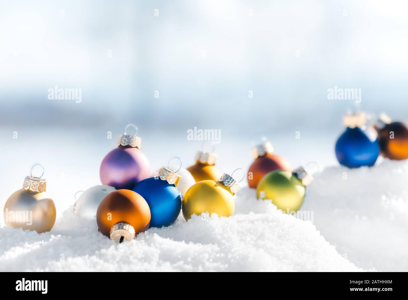 Boules colorées ou boules de noël couchées dans la neige, paysage d'hiver fond avec espace de copie Banque D'Images