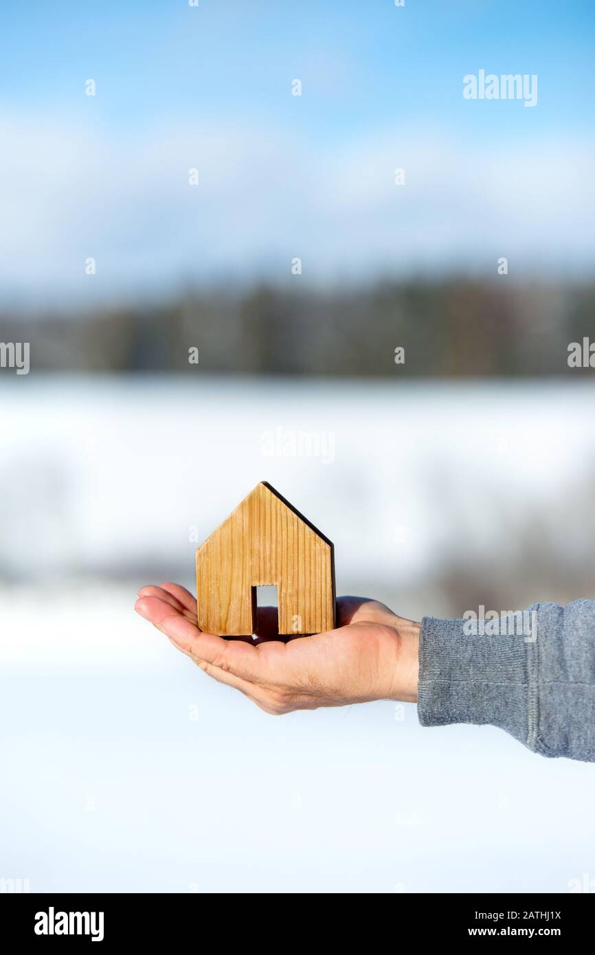 Homme tenant une petite maison, terre de bâtiment de propriété en arrière-plan, planification et idée, copyspace Banque D'Images