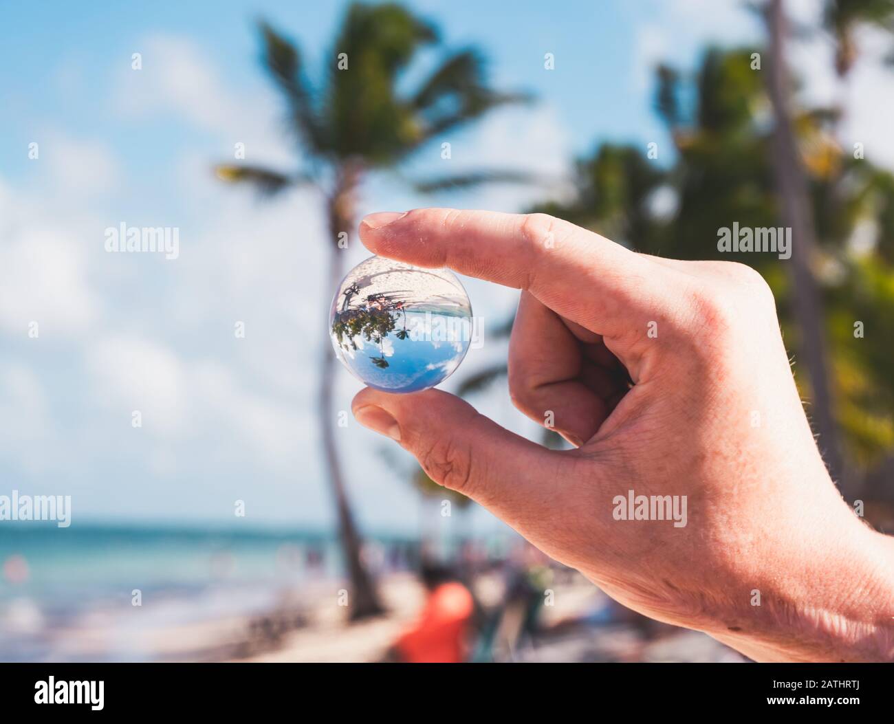 Main De La Personne Qui Tient Mini Boule De Verre Et Fond De Plage Banque D'Images