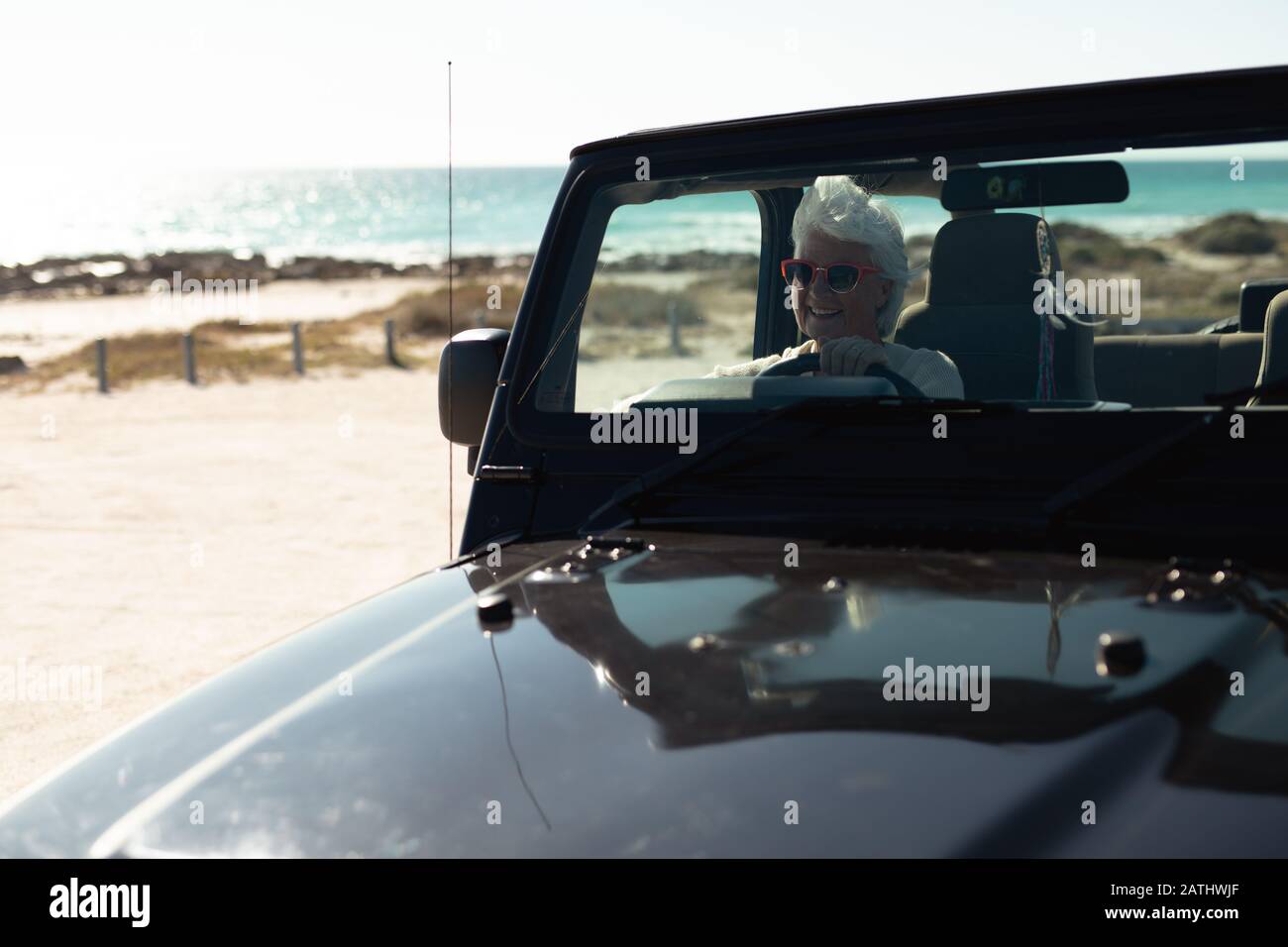 Vieille femme en voiture à la plage Banque D'Images