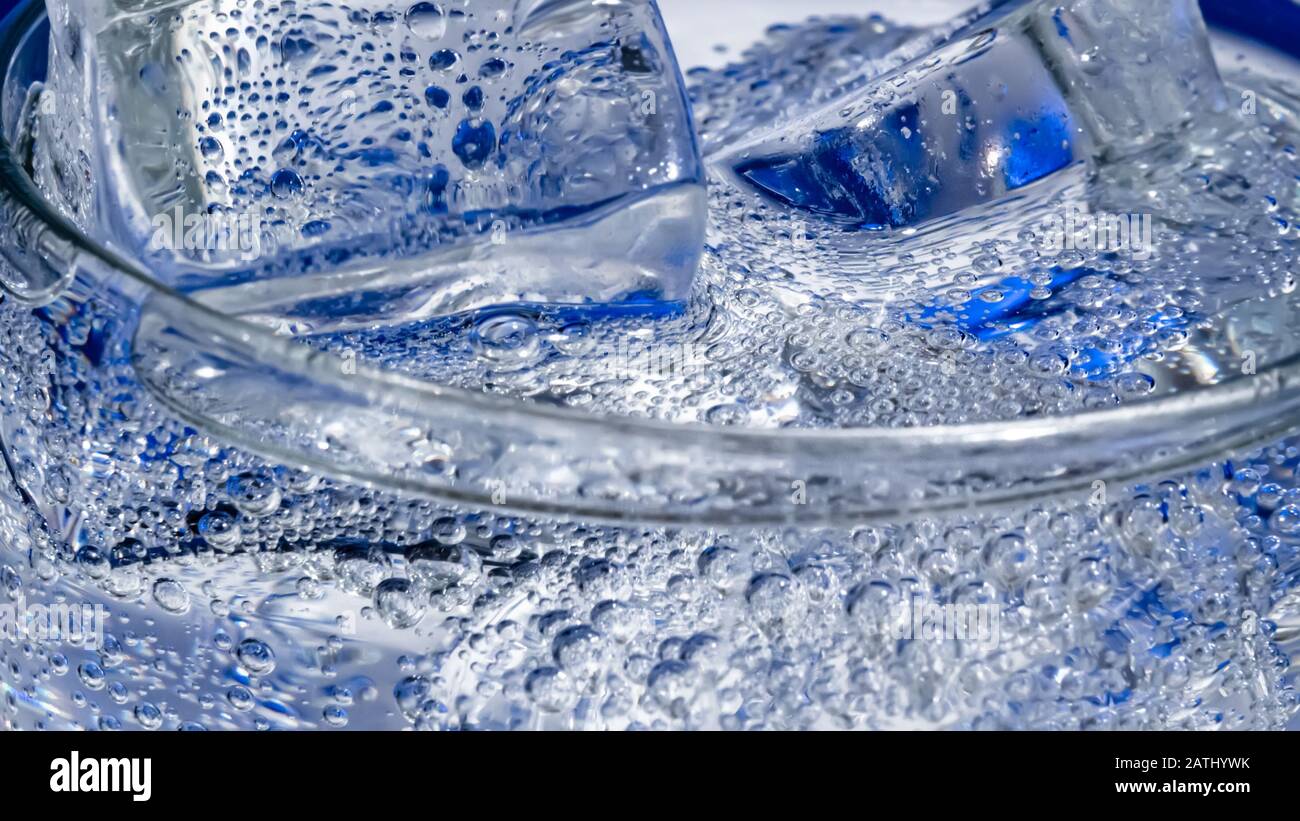 Verre d'eau avec de la glace sur un fond bleu foncé Banque D'Images