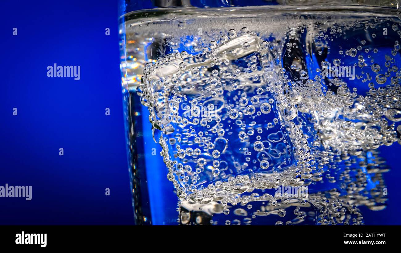 Verre d'eau avec de la glace sur un fond bleu foncé Banque D'Images