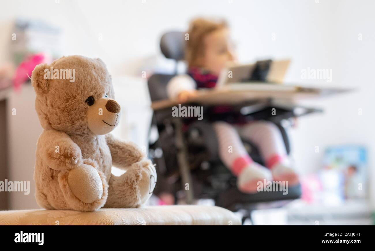 03 février 2020, Bade-Wuerttemberg, Backnang: Un ours en peluche est assis devant un enfant avec atrophie musculaire spinale (SMA) assis dans une chaise de thérapie. Photo: Sebastian Gollnow/Dpa Banque D'Images