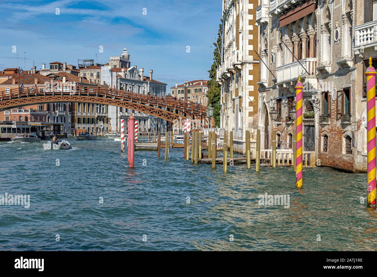 Poteaux d'amarrage en bois à rayures colorées sur le Grand Canal de Venise avec le pont Ponte dell'Accademia en arrière-plan Banque D'Images