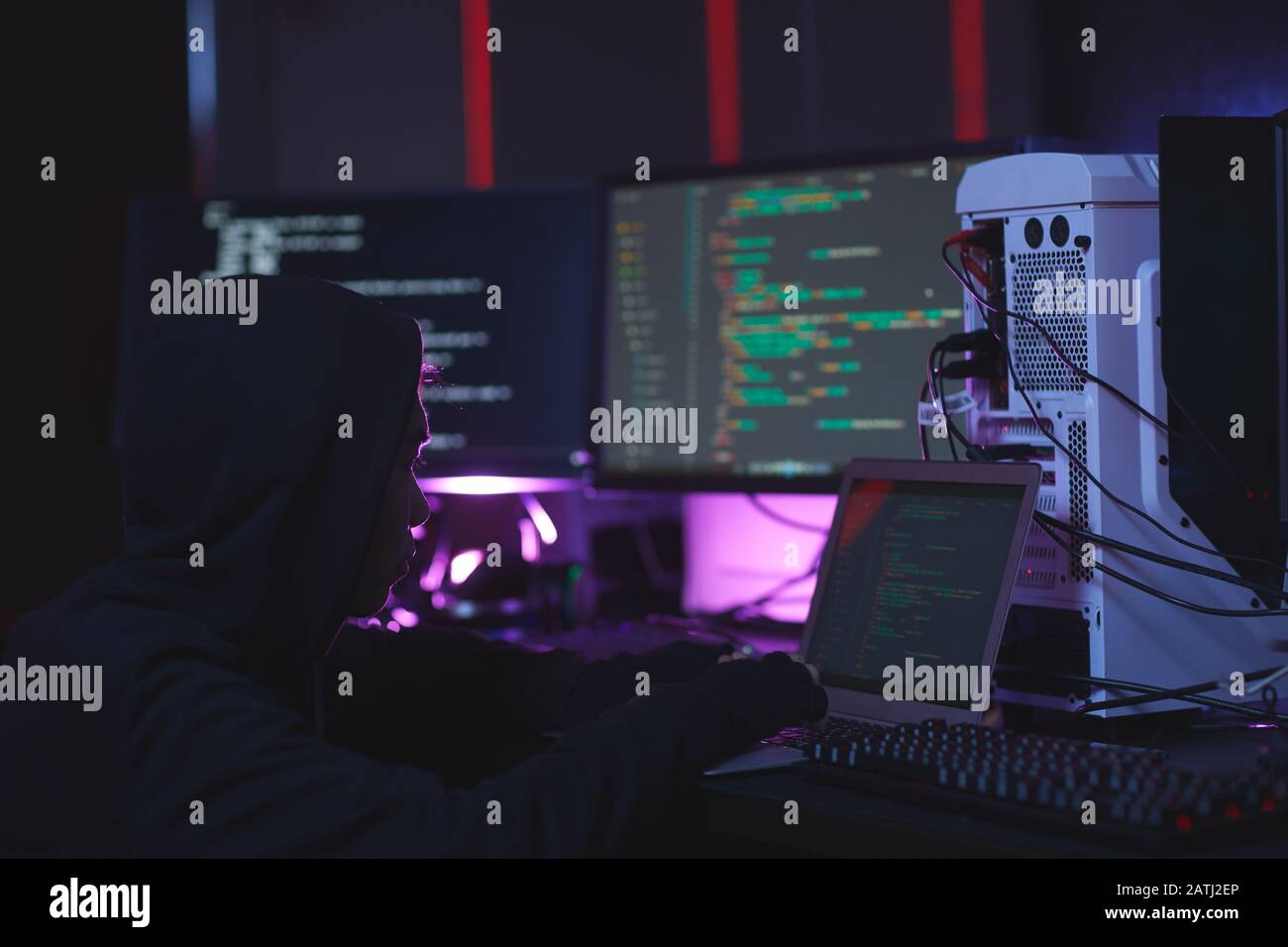 Portrait d'un pirate non reconnaissable utilisant un équipement informatique avec code de programmation sur les écrans dans la salle sombre, concept de cyber-sécurité, espace de copie Banque D'Images