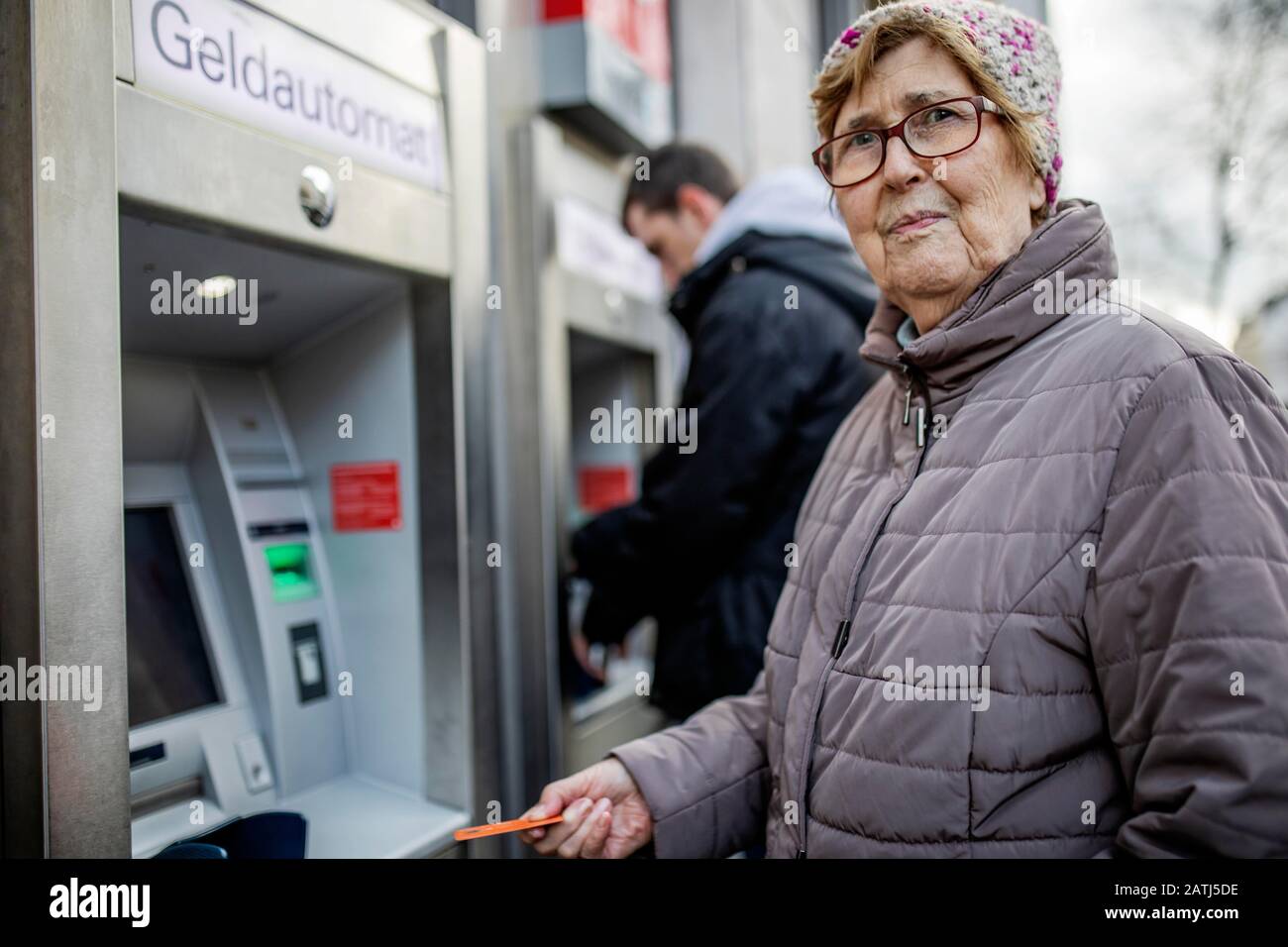 Le citoyen senior avec carte de paiement à l'guichet automatique est sceptique, Cologne, Rhénanie-du-Nord-Westphalie, Allemagne Banque D'Images