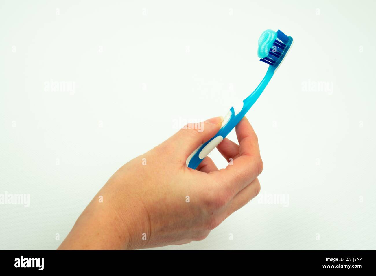 main femelle tenant une brosse à dents avec dentifrice isolé sur un fond blanc. Banque D'Images