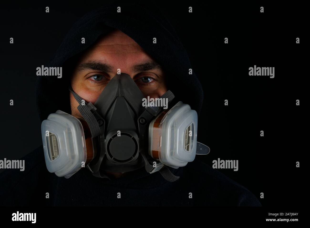 Portrait d'un homme adulte avec masque anti-poussière qui se fixe à l'appareil photo sur fond noir Banque D'Images