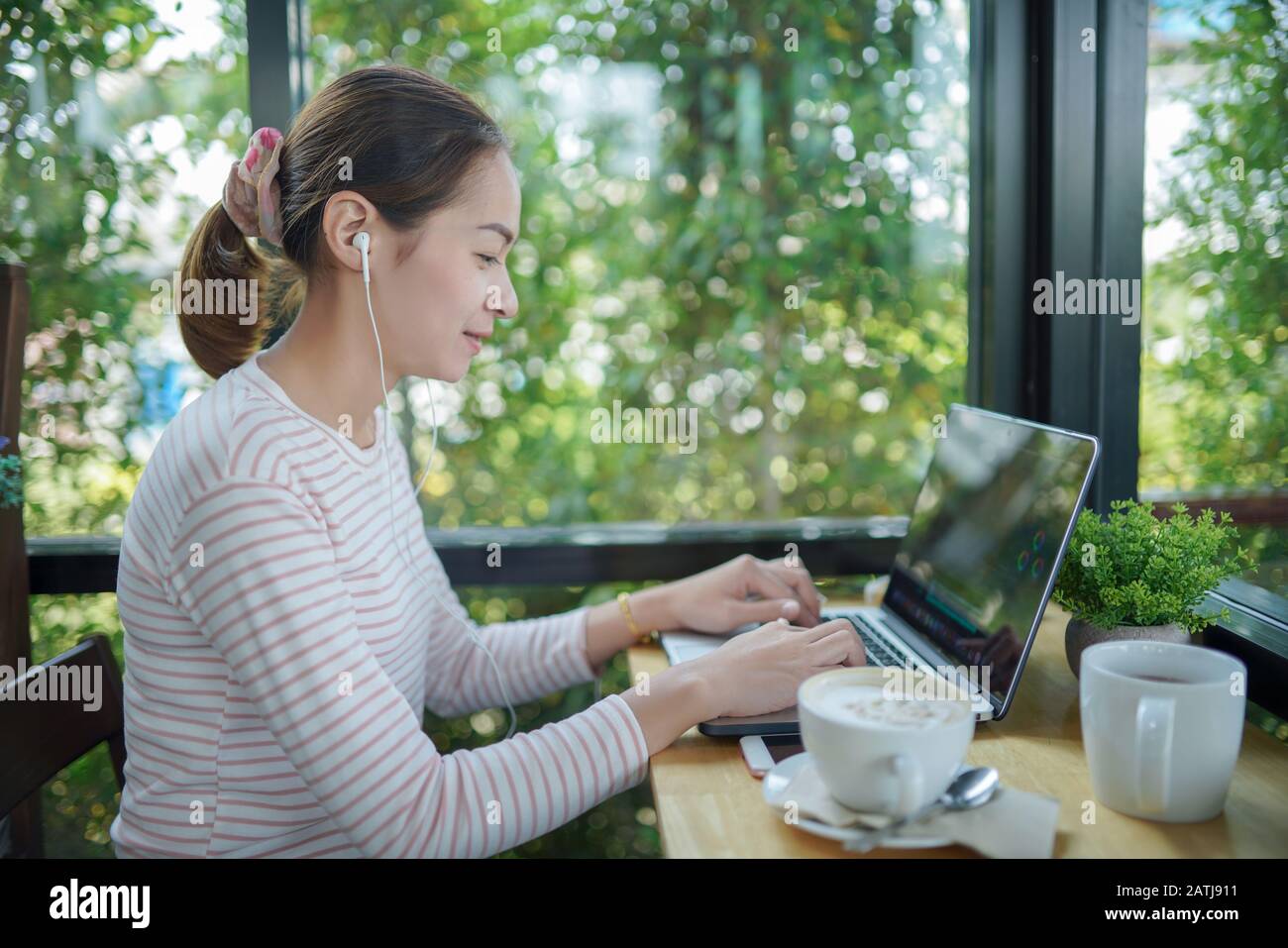 Jeune femme freelance utiliser un ordinateur portable et casque montage vidéo dans la boutique de café C'est le style de vie du créateur de contenu Banque D'Images