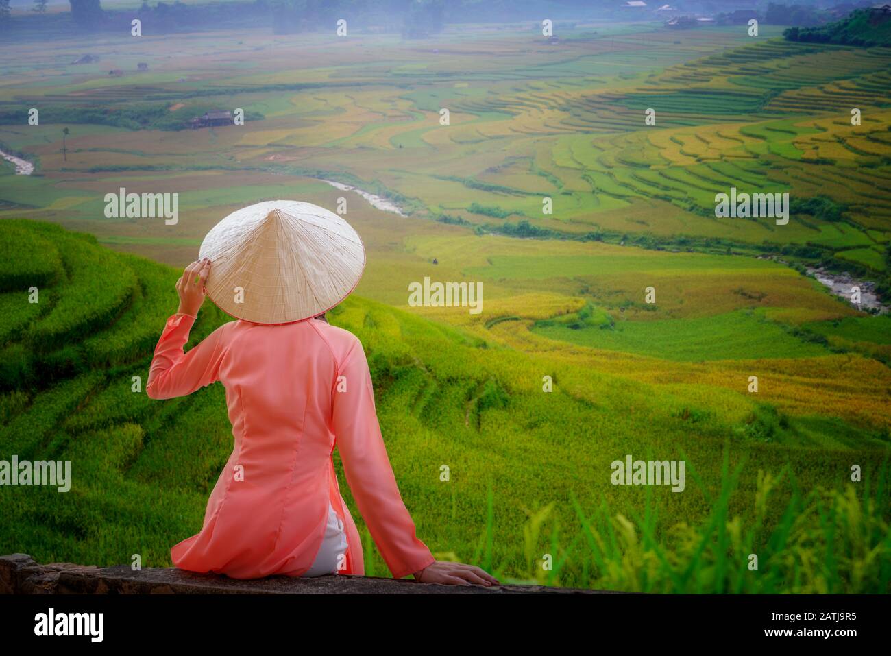 Vietnamienne UNE femme portant Ao Dai Vietnam robe traditionnelle et assis regardant la belle terrasse de riz vue sur le paysage à Tu le Yen Bai Vietnam Banque D'Images