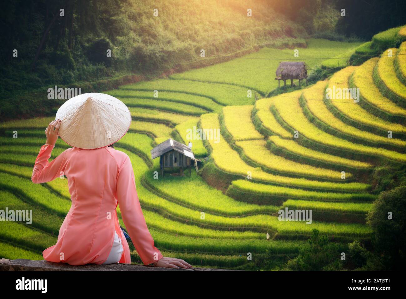 Femme de tourisme portant Ao Dai Vietnam robe traditionnelle assis regardant la terrasse de riz beau paysage dans Mu Cang Chai Vietnam. Banque D'Images