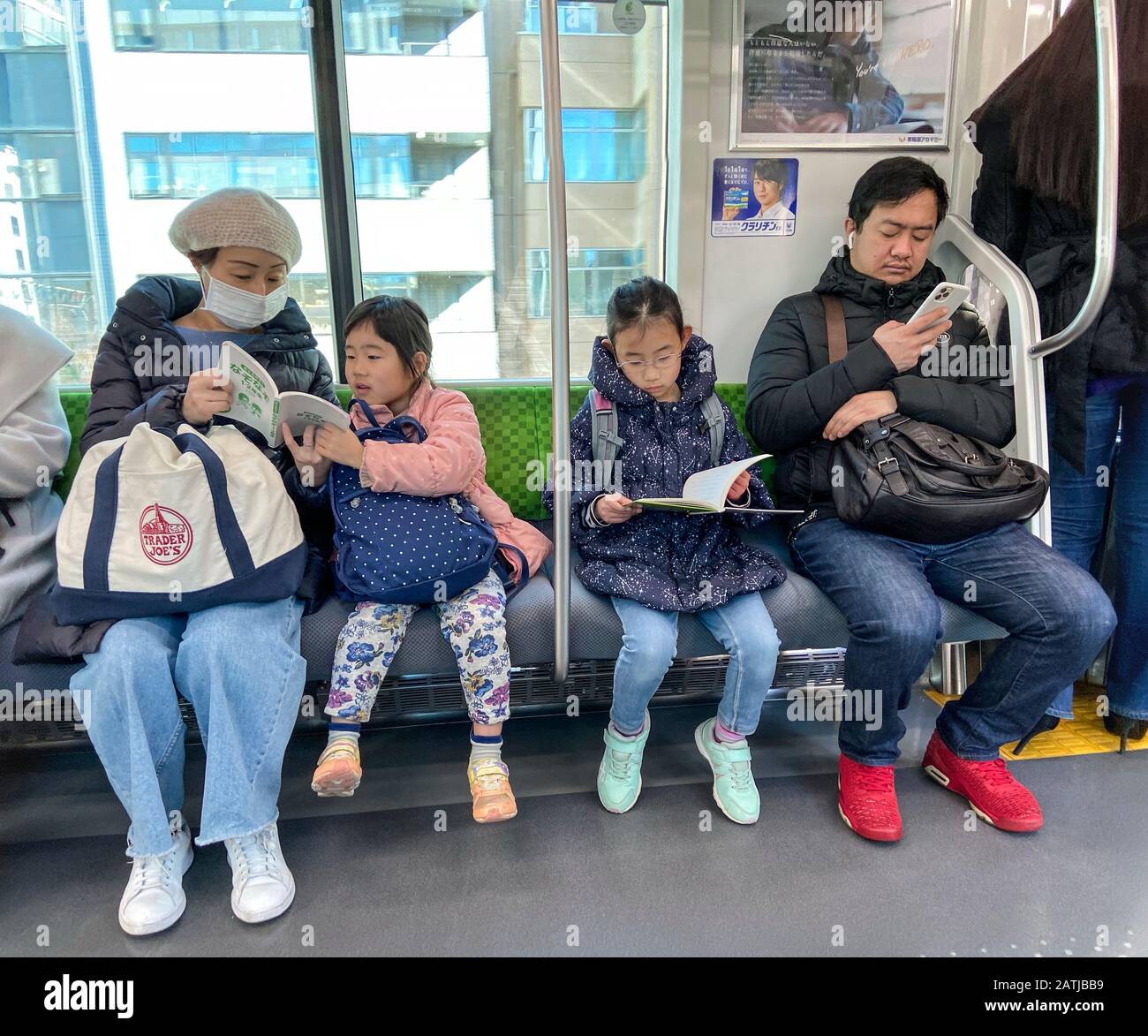 LECTURE EN FAMILLE DANS LE MÉTRO TOKYO, JAPON Banque D'Images