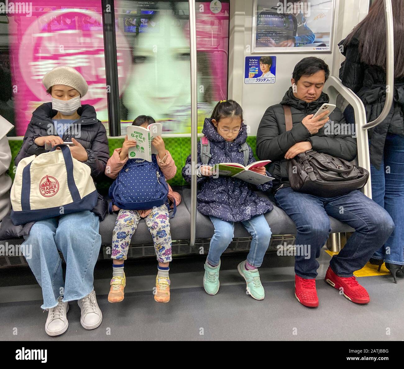 LECTURE EN FAMILLE DANS LE MÉTRO TOKYO, JAPON Banque D'Images