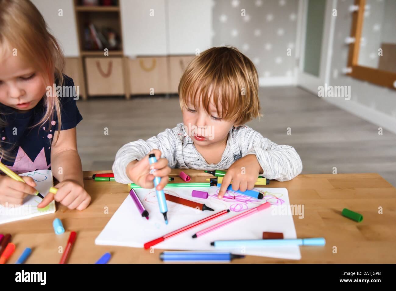 Petit garçon avec dessin de sœur et stylos-feutres Banque D'Images