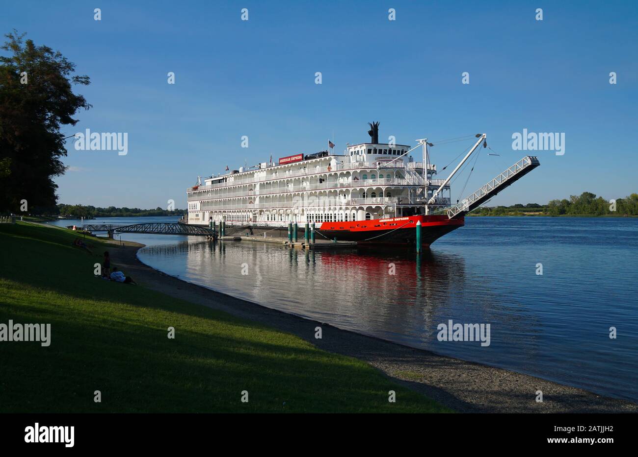 Un beau vieux paddleboat est amarré le long d'un parc en bord de rivière lors d'une journée d'été paresseuse. Banque D'Images