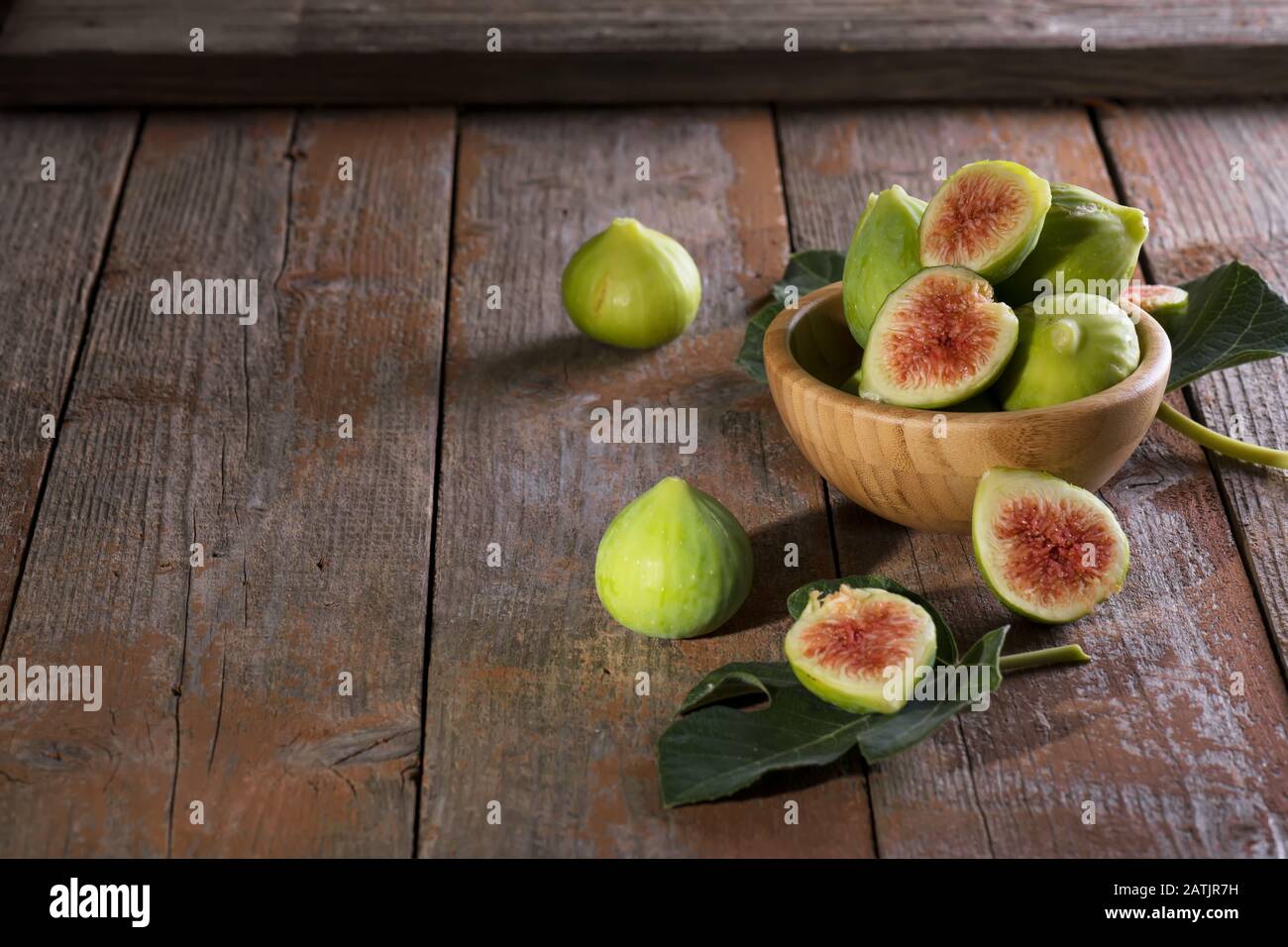 Figues vertes mûres avec feuilles vertes. Fruit de figue méditerranéenne sain sur un chien de fond en bois, fabriqué dans les Pouilles, en Italie Banque D'Images