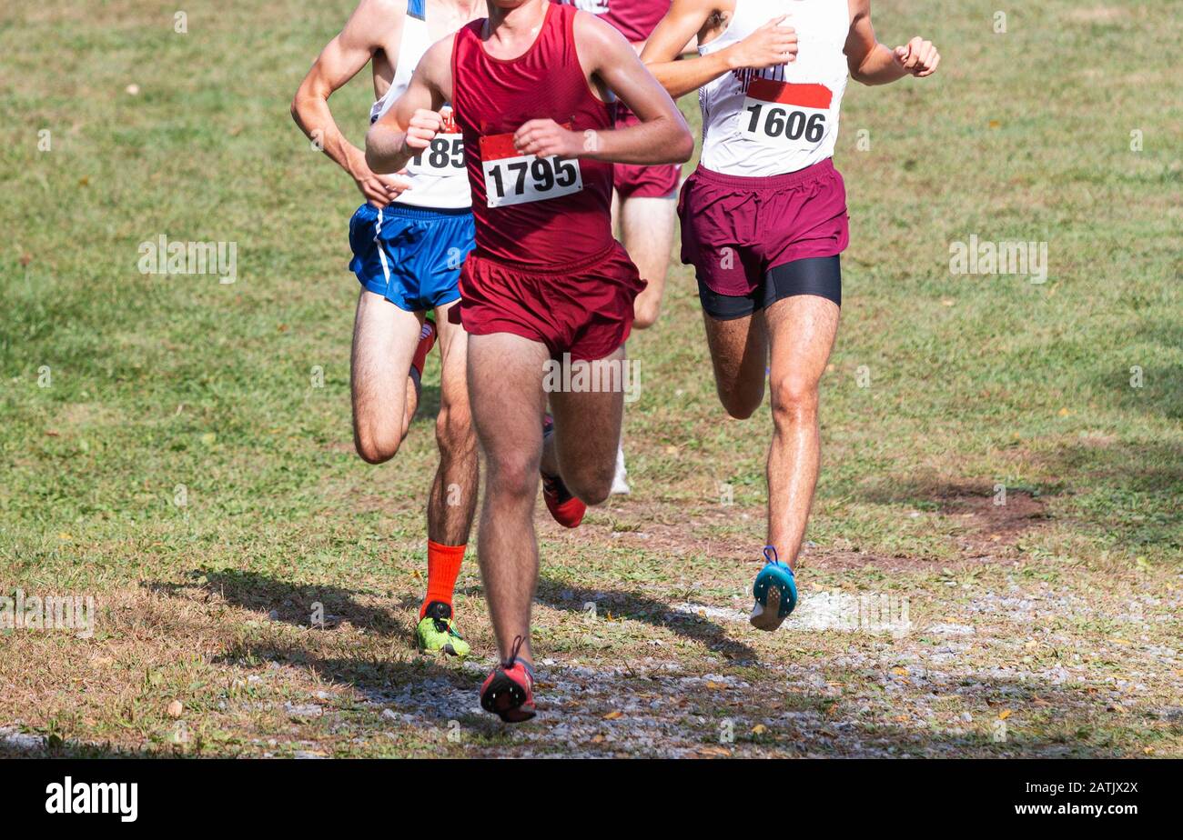 Quatre garçons du lycée qui descendent rapidement et étroitement ensemble pendant une course de cross-country au parc Bowdoin à New York. Banque D'Images