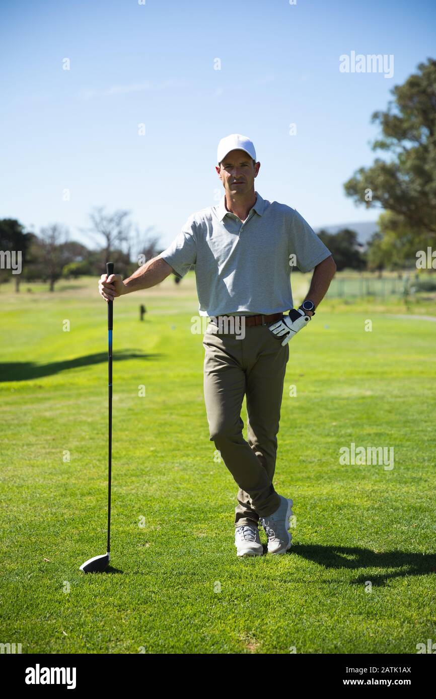 Golfeur regardant l'appareil photo et tenant le club de golf Banque D'Images