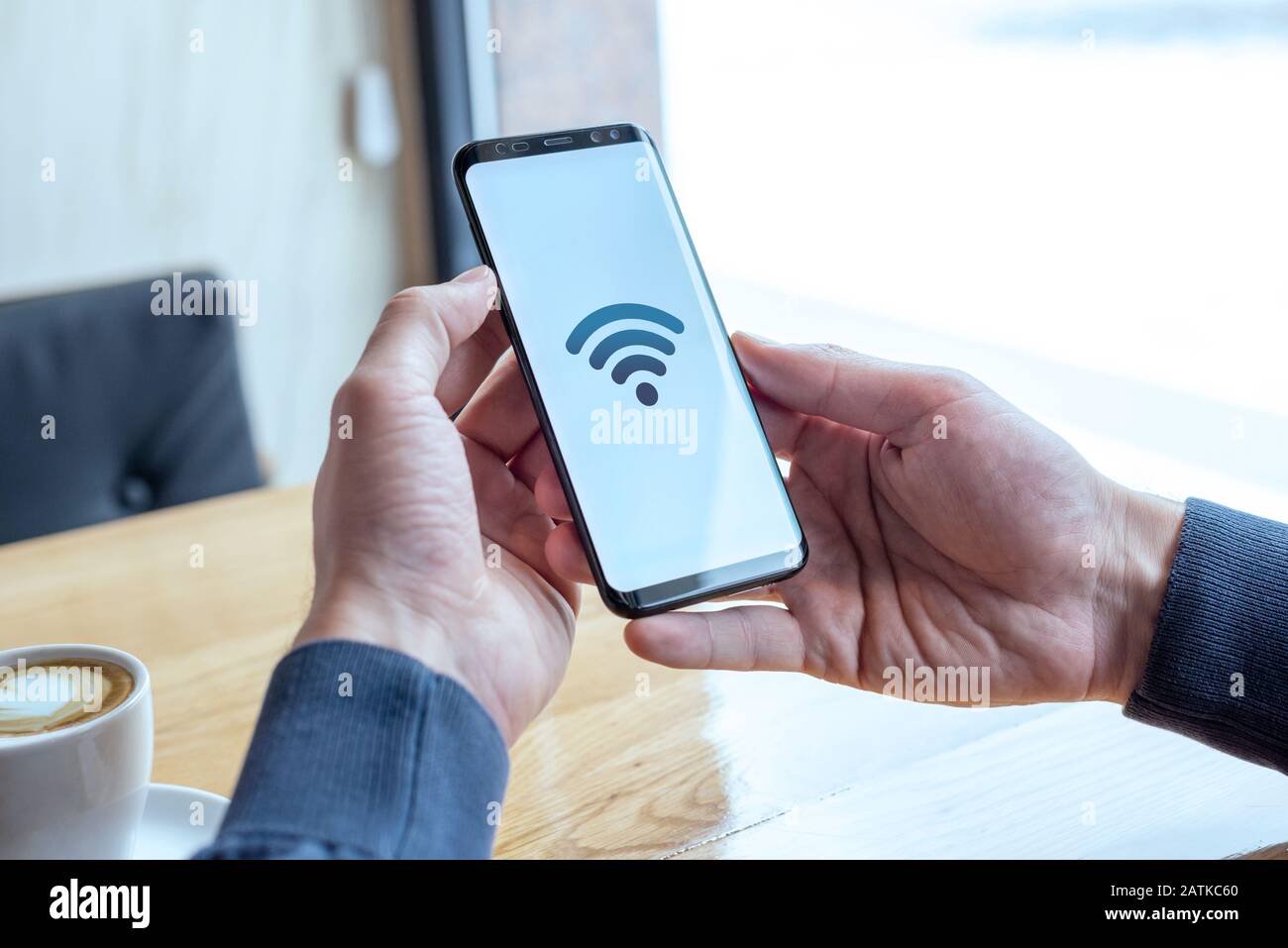 Icône de concept Wi-fi sur l'écran du smartphone. Les mains tenant le téléphone portable dans le café. Le concept d'Internet gratuit et de connexion globale Banque D'Images