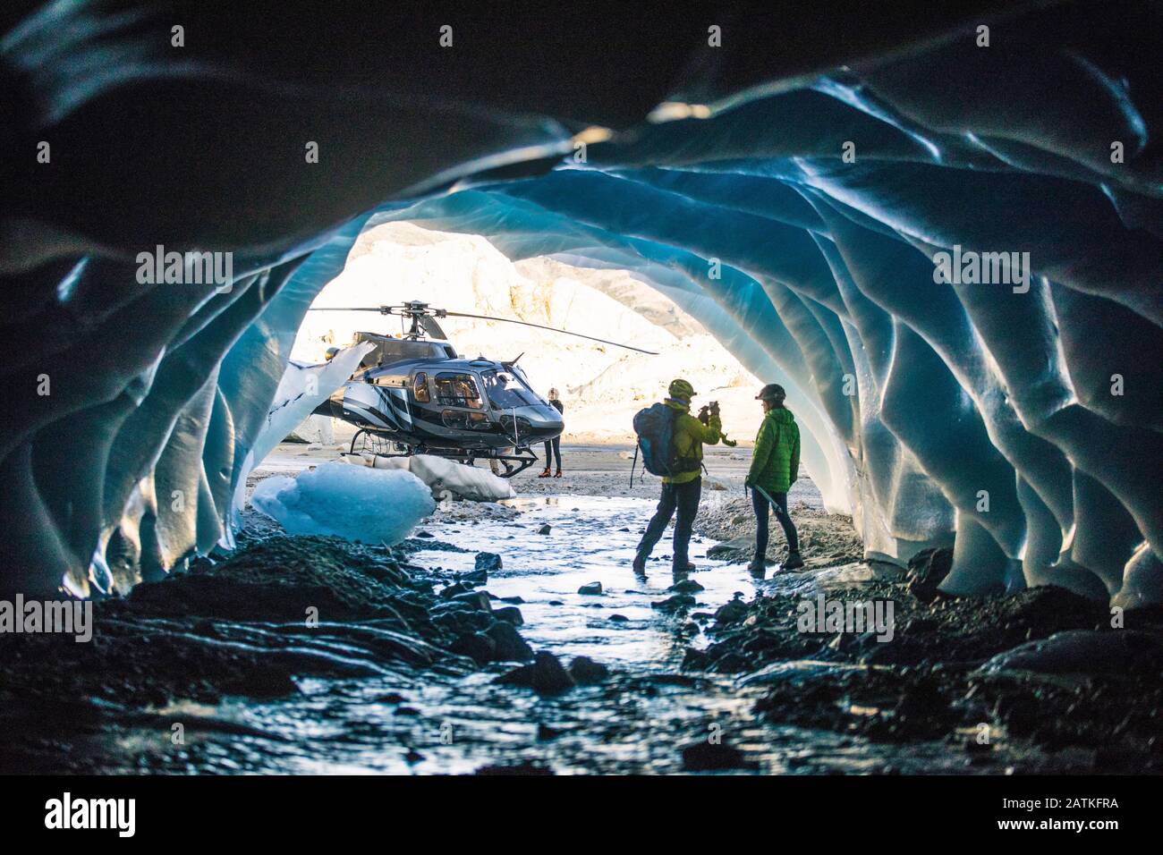 Homme photographiant partenaire dans une grotte de glace pendant le vol en hélicoptère. Banque D'Images