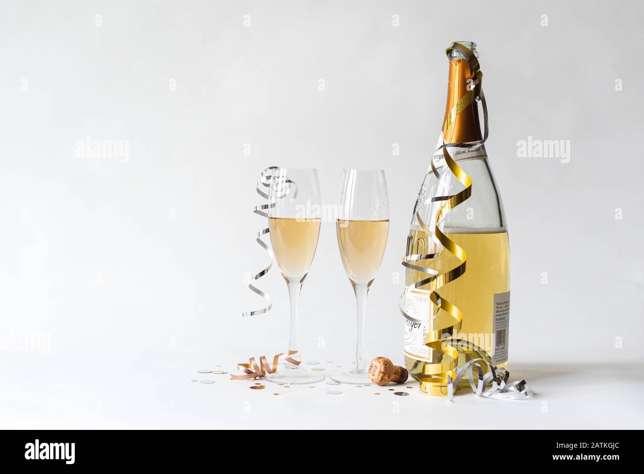 Deux verres à champagne et une bouteille sur fond blanc. Banque D'Images