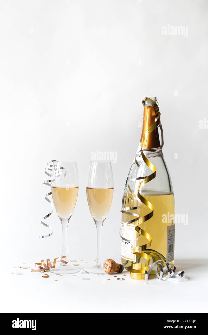 Deux verres à champagne et une bouteille sur fond blanc. Banque D'Images