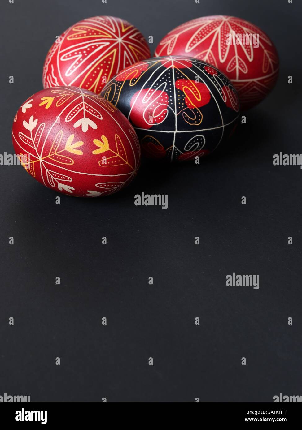 Groupe de quatre oeufs de pâques roumains peints en rouge et en noir isolés sur fond noir, orientation portrait, espace texte, faits à la main Banque D'Images