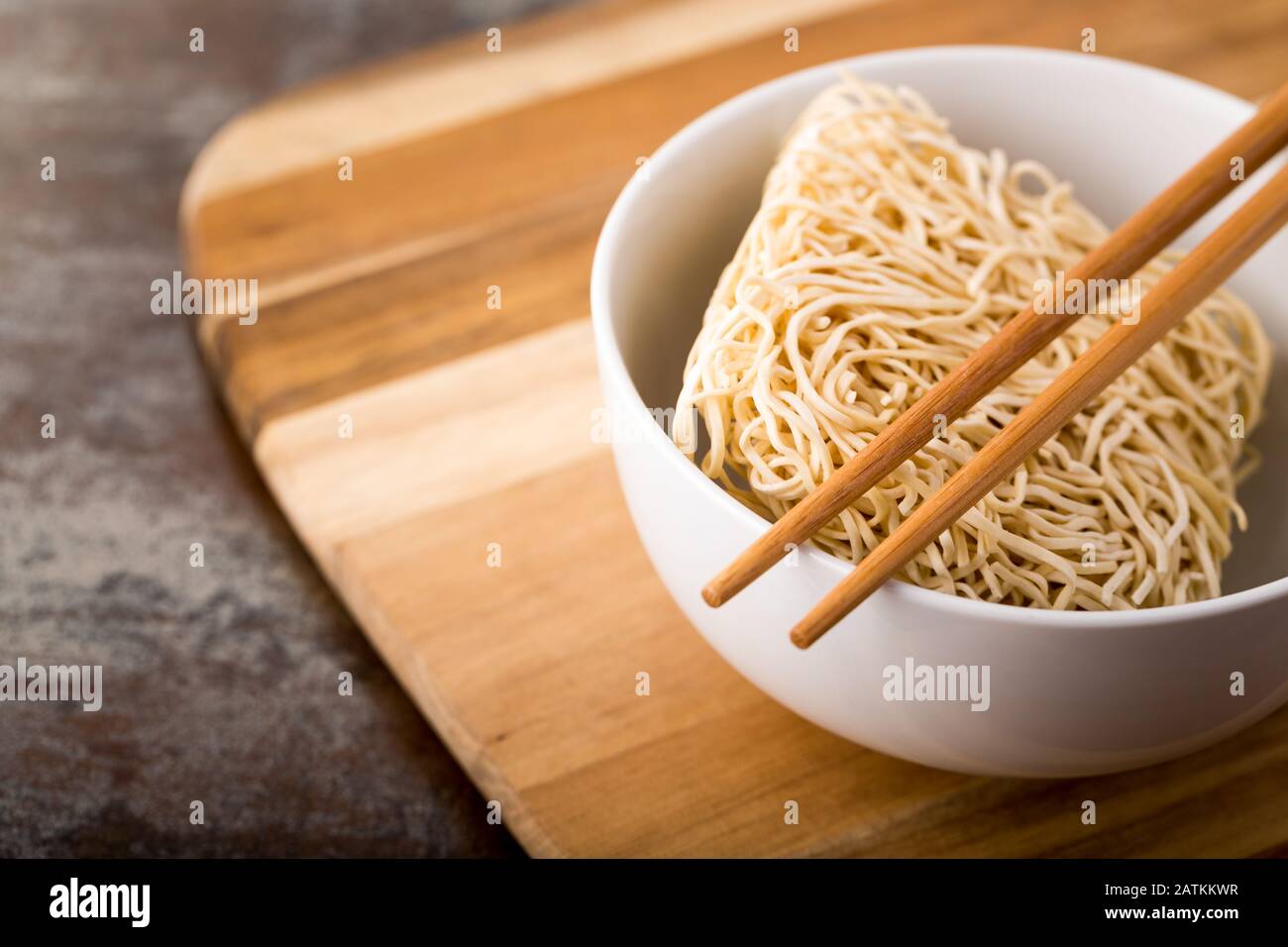 Nouilles chinoises séchées dans un bol. Bâtonnets de bambou. Cuisine asiatique. Banque D'Images