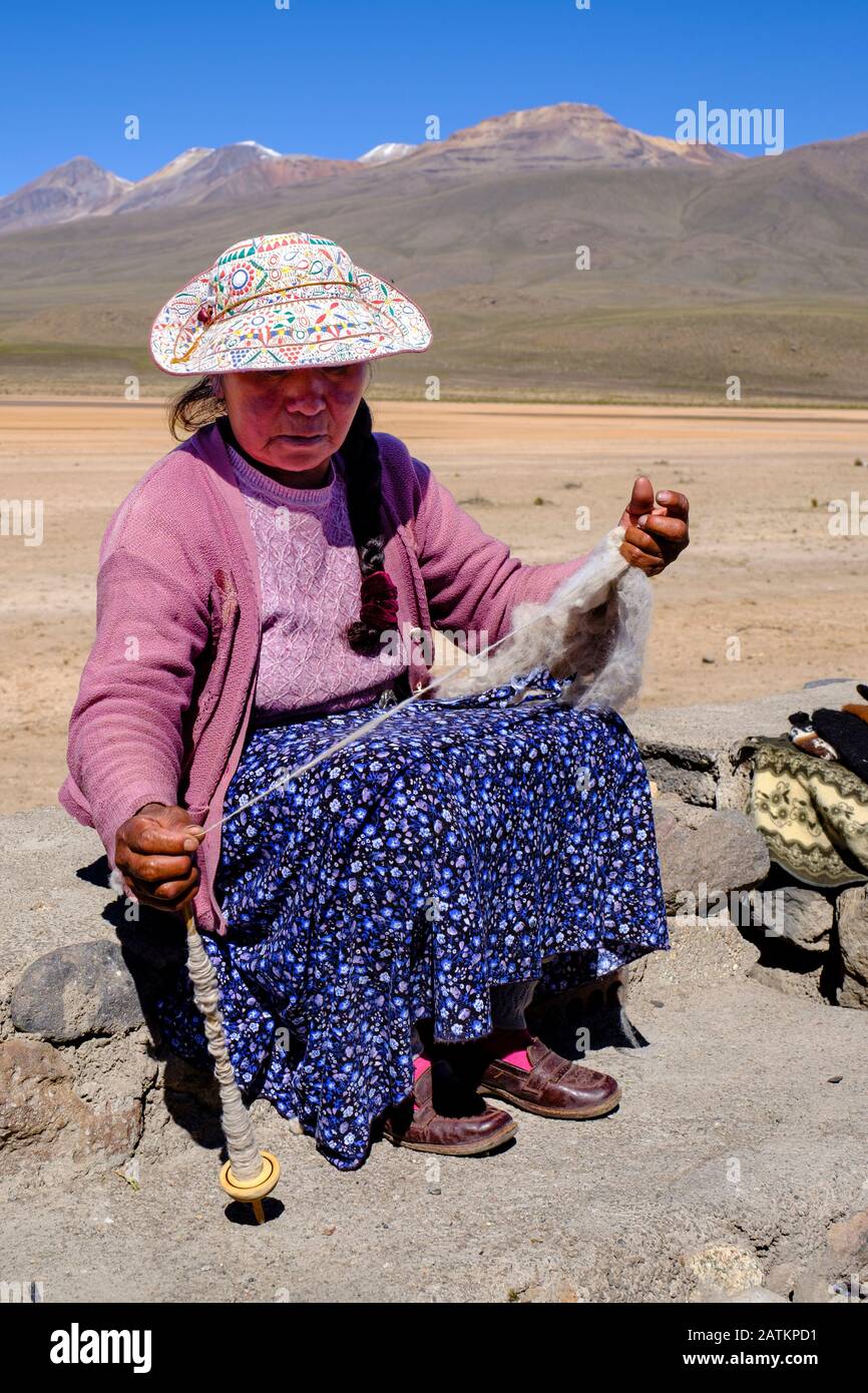 Une femme péruvienne qui fait tourner de la laine portant un chapeau brodé traditionnel, le Canyon Colca, Salinas et La Réserve nationale Aguada Blanca, plateau andin Pérou Banque D'Images