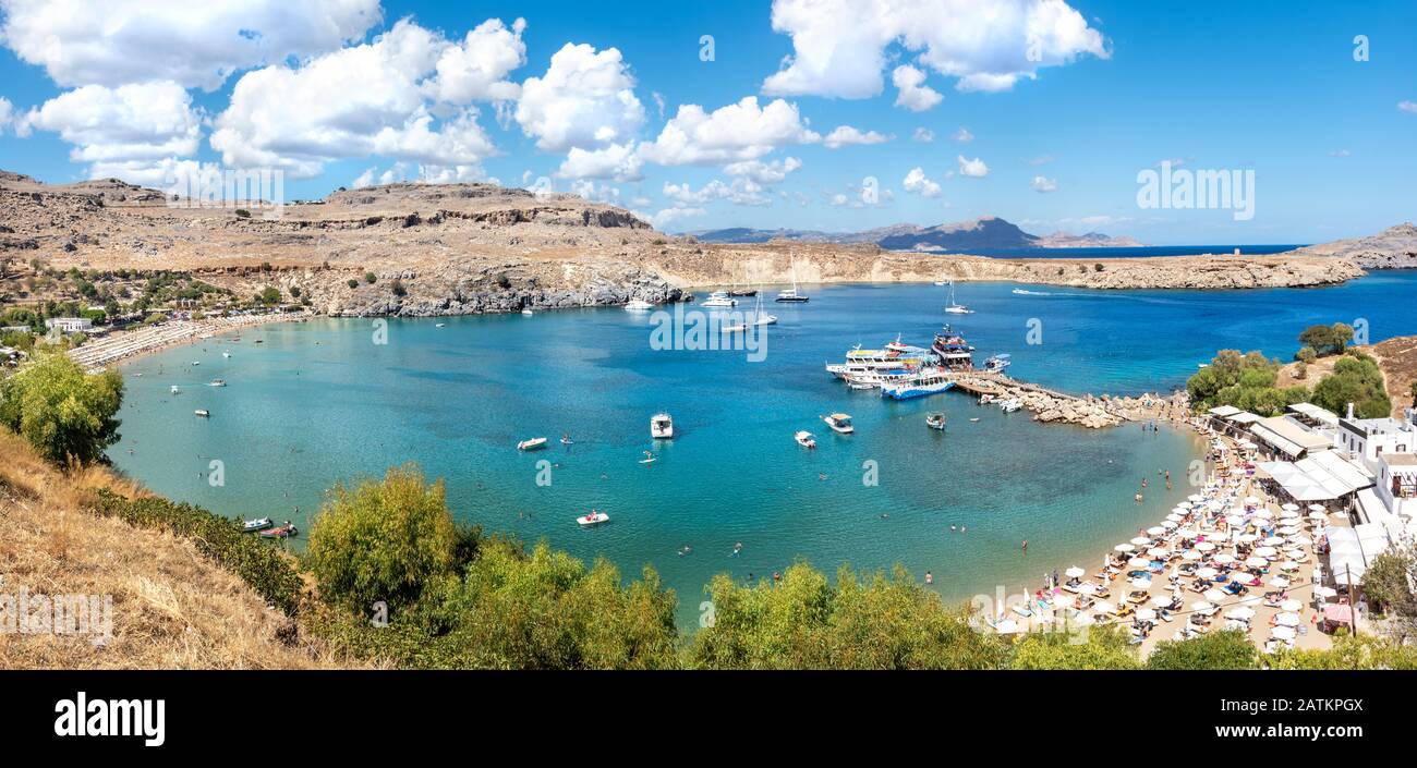 Petite plage dans la baie de Lindos avec vacanciers et jetée avec bateaux touristiques (Rhodes, Grèce) Banque D'Images