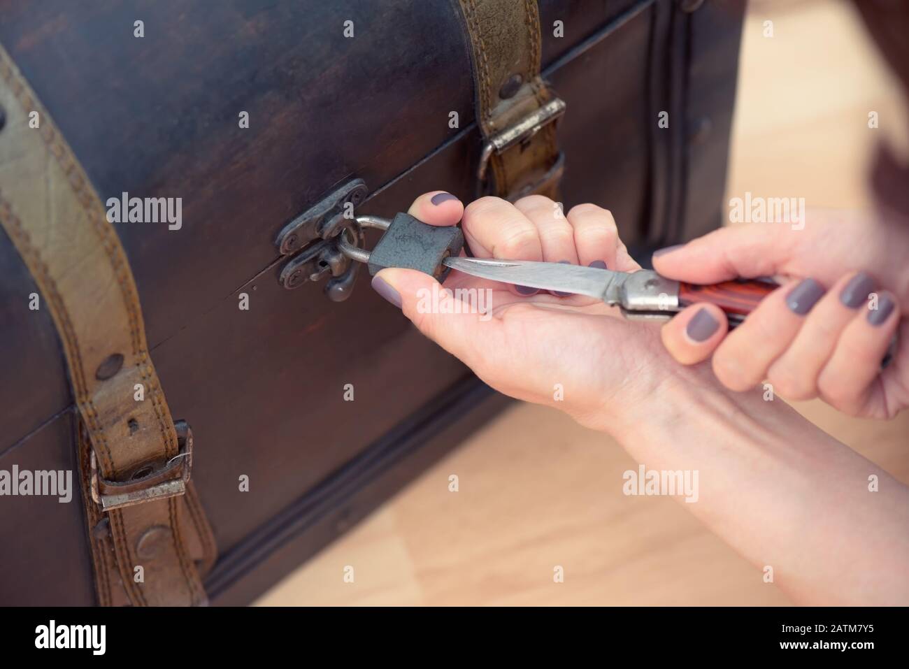 Gros plan sur les mains de la femme ouvrant une vieille poitrine avec un couteau Banque D'Images