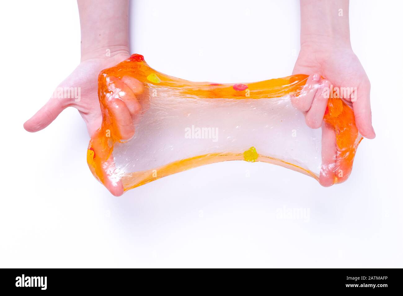 Fille s'étirant à la chaux orange colorée sur les côtés. Les mains des enfants jouent au jouet de chaux vive sur fond blanc. Faire de la chaux vive Banque D'Images