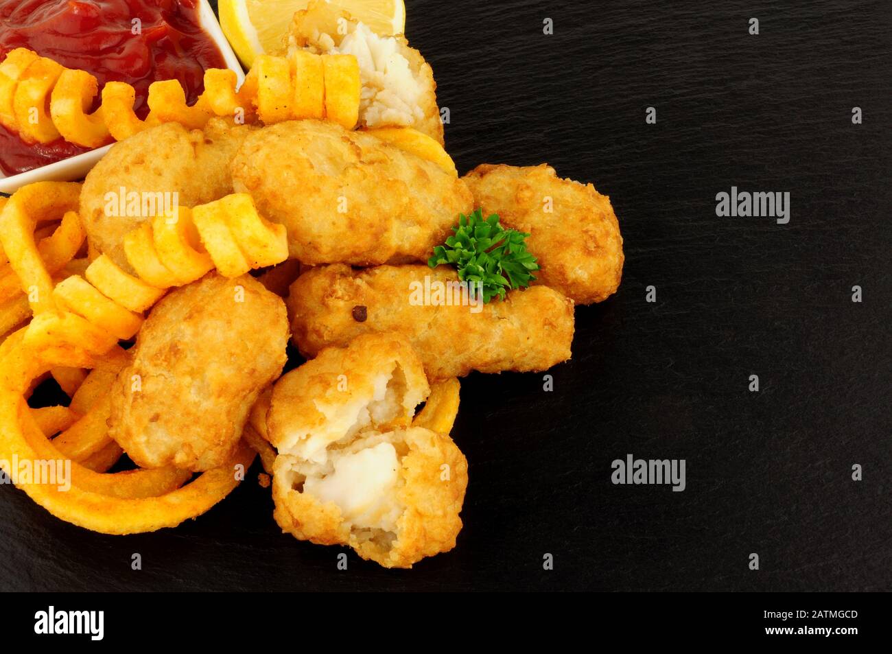 Les pépites de morue battues avec des frites cureuses sur fond de pierre d'ardoise Banque D'Images
