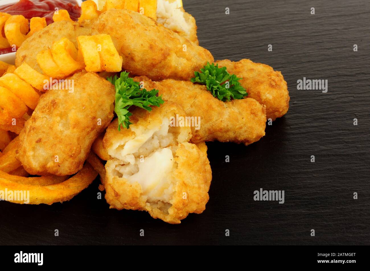 Les pépites de morue battues avec des frites cureuses sur fond de pierre d'ardoise Banque D'Images