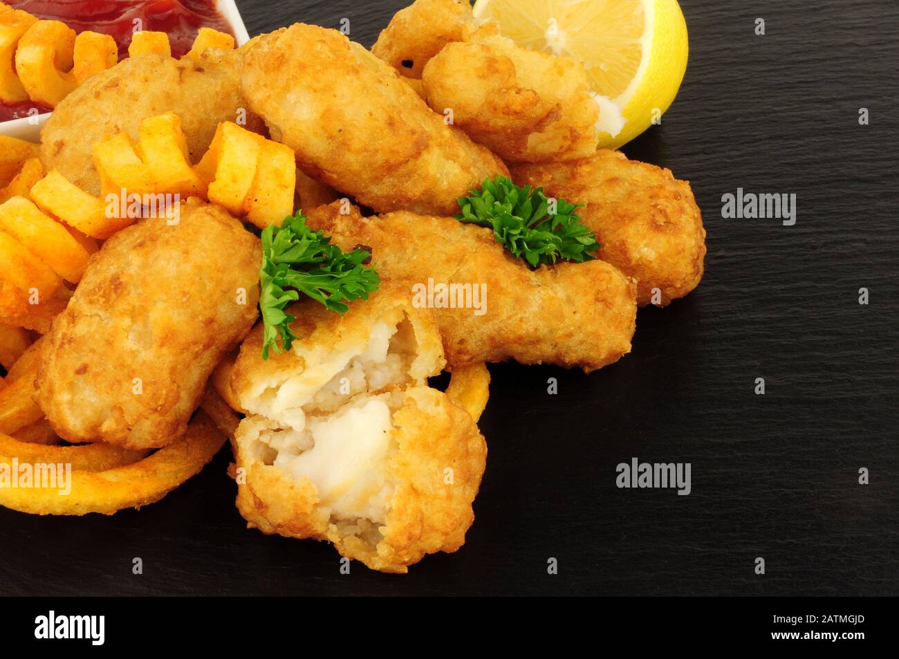 Les pépites de morue battues avec des frites cureuses sur fond de pierre d'ardoise Banque D'Images